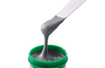 Grey paste being scooped from a green jar.