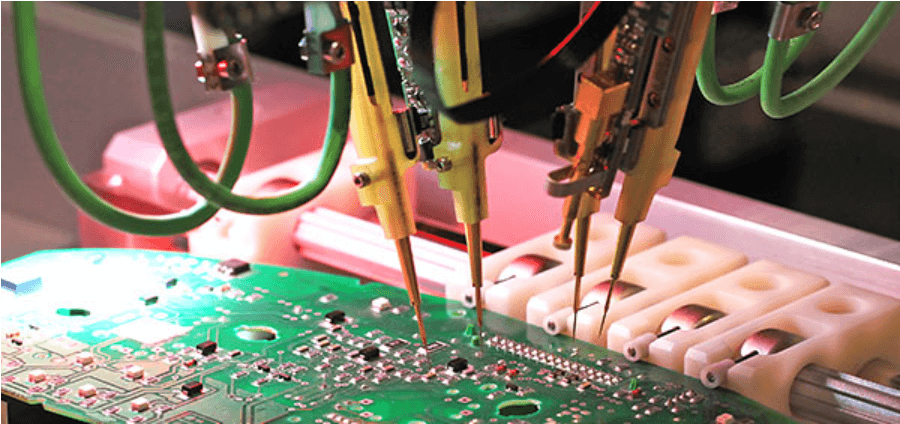 The image depicts a close-up view of a specialized machine tool engaged in operations on a green printed circuit board (PCB). The machine tool is characterized by its green body and an array of connections that include green and perhaps yellow wires or tubes that extend to the image's periphery. Alongside these, there are six yellow components, which could be nozzles or electrical test probes, that interact directly with the circuit board suggesting a process that requires accuracy and might involve testing or printing functions on the PCB. The complexity and precision of the machinery suggest that it is part of an electronic manufacturing or assembly line.