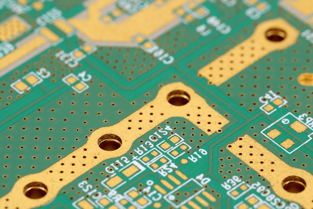 The image showcases a close-up view of a detailed circuit board with green and gold colors. It features numerous small holes and gold-plated sections, highlighting gold's role as a conductor. The intricate details of the circuit board stand out against a blurred or white background, creating a technical and abstract atmosphere that represents the complexity and precision of modern technology.