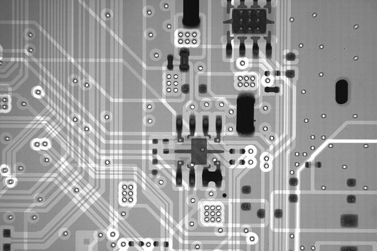 X-ray style image of a black and white electronic circuit board. Grid pattern with lines, circles, and electronic components. Four dark rectangular components, possibly transistors, arranged in a square. Dark rectangular box, potentially an integrated circuit. Dark circle, possibly a via or pad. Intricate design with holes and lines indicating connections. Luminescence effect illuminates the board from the top left, casting shadows and highlighting textured surface.
